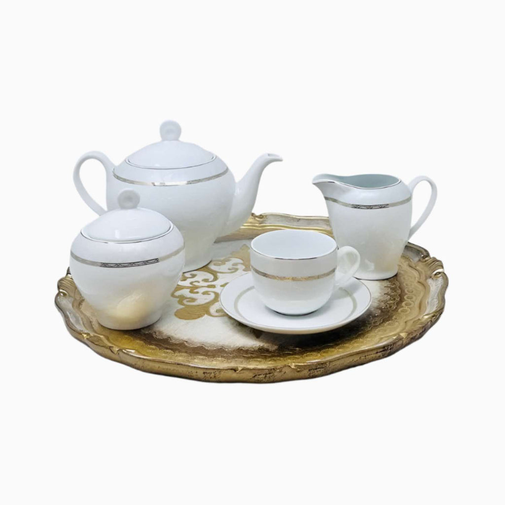 White ceramic tea set with gold accents on a decorative tray against a white background