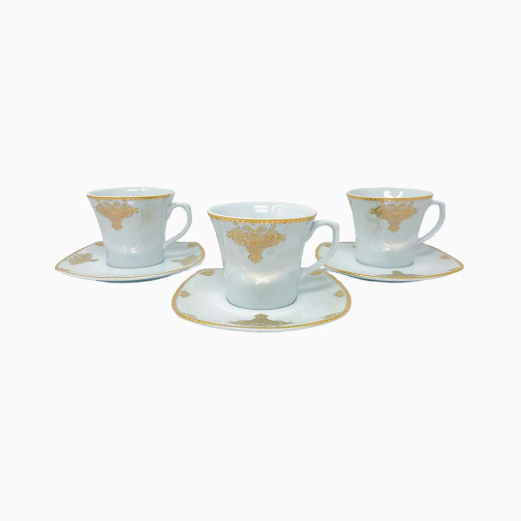 Set of three white cups with gold decorative elements on saucers against a white background