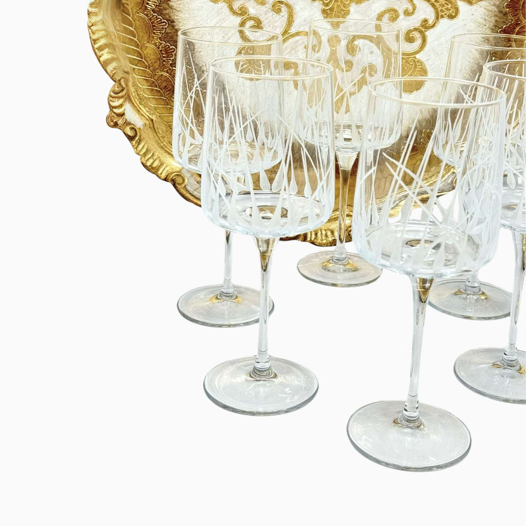 Set of crystal wine glasses with a decorative gold platter in the background