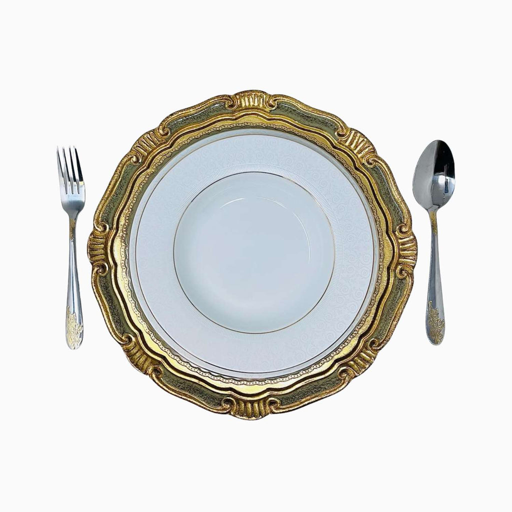 Decorative gold-rimmed plate with a white center, accompanied by a fork and spoon on a white background.