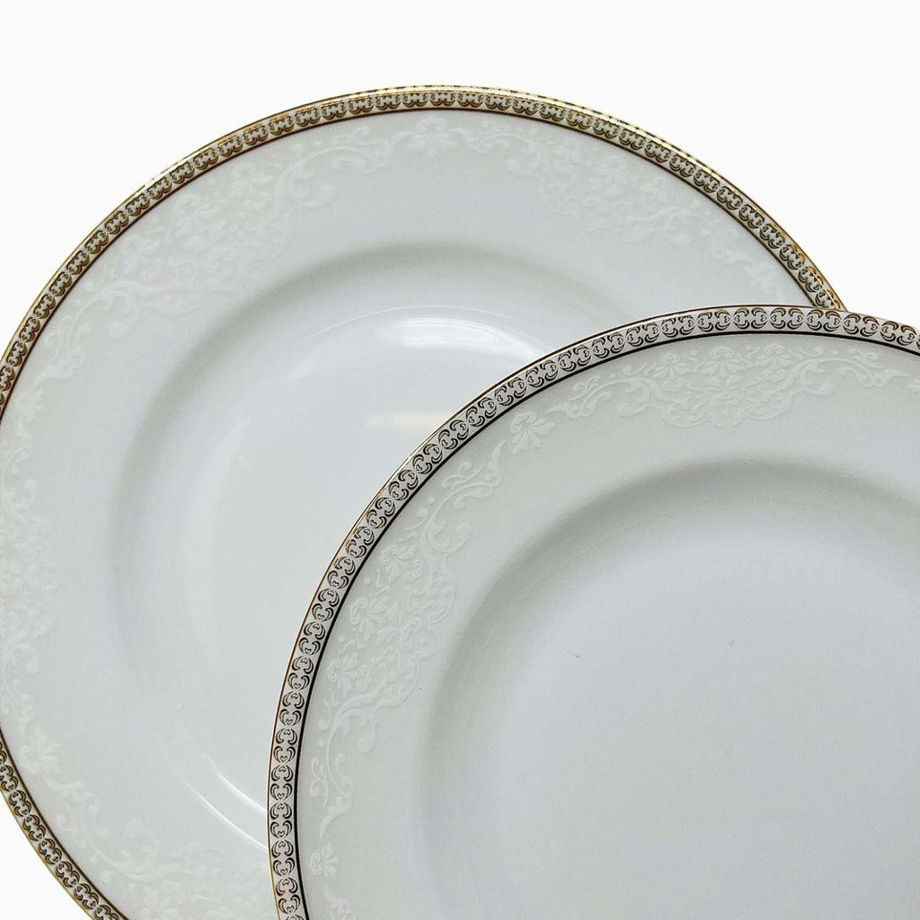 Two white dinner plates with decorative gold rims on a white background