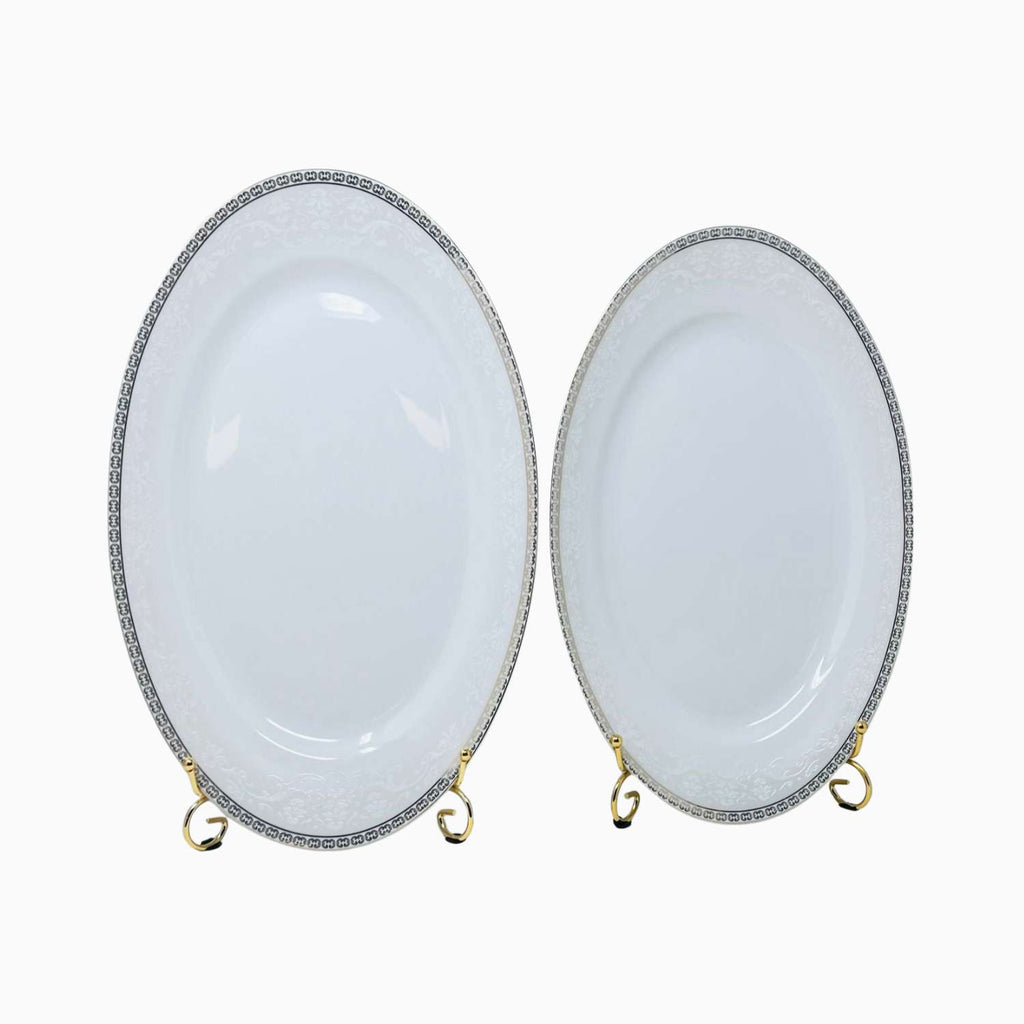 Two oval ceramic plates with decorative rims on a white background