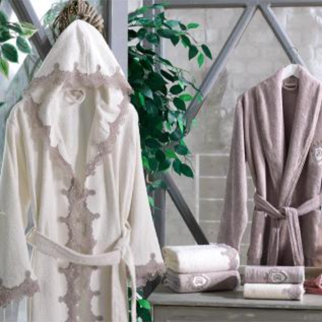 A cream and mauve colored eight-piece bathrobe set displayed in a home setting, including bathrobes and towels.