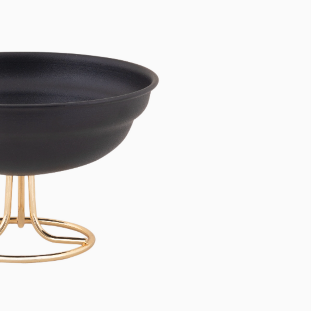 Black bowl on a gold stand against a white background