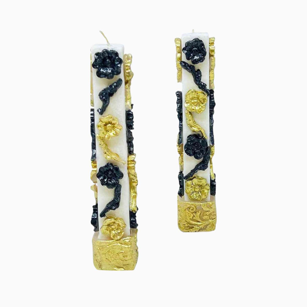 Decorative candles with gold and black floral patterns on a white background