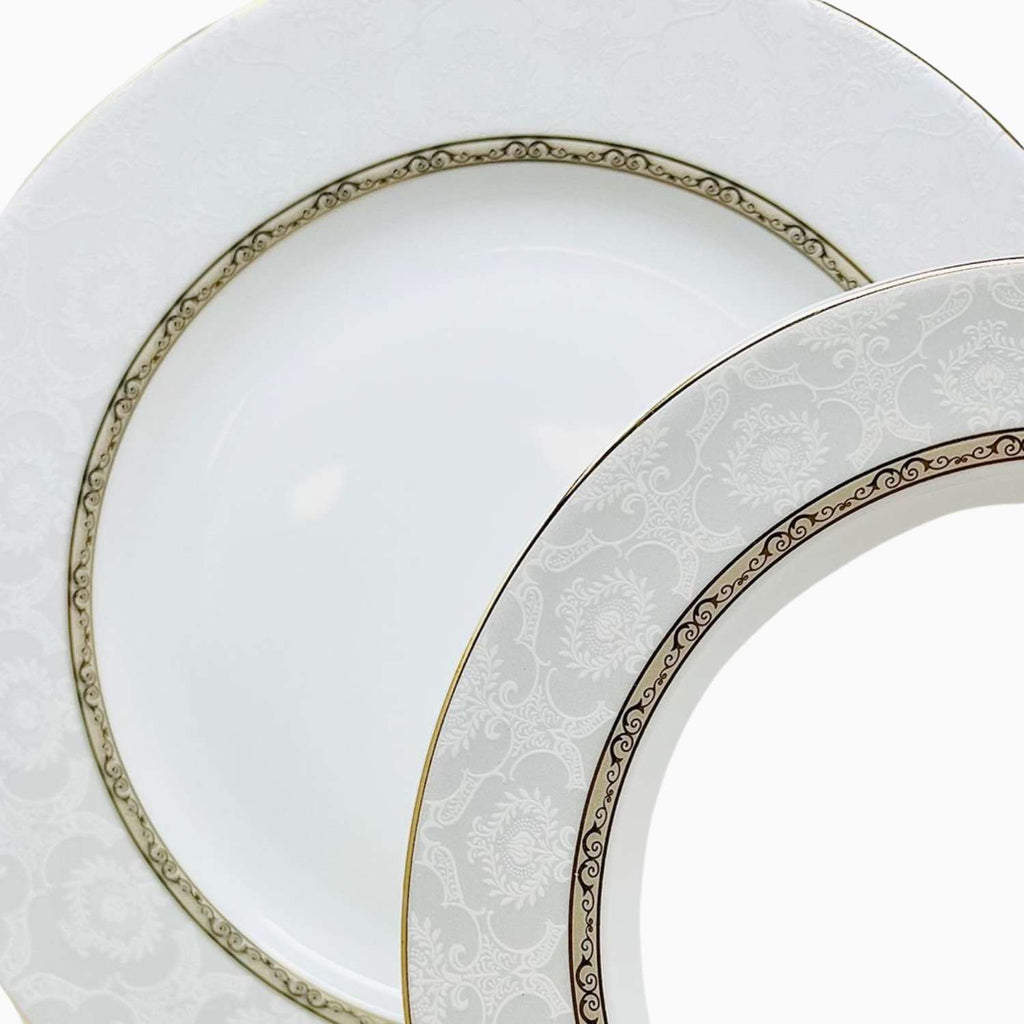 Two white plates with decorative gold rims on a white background