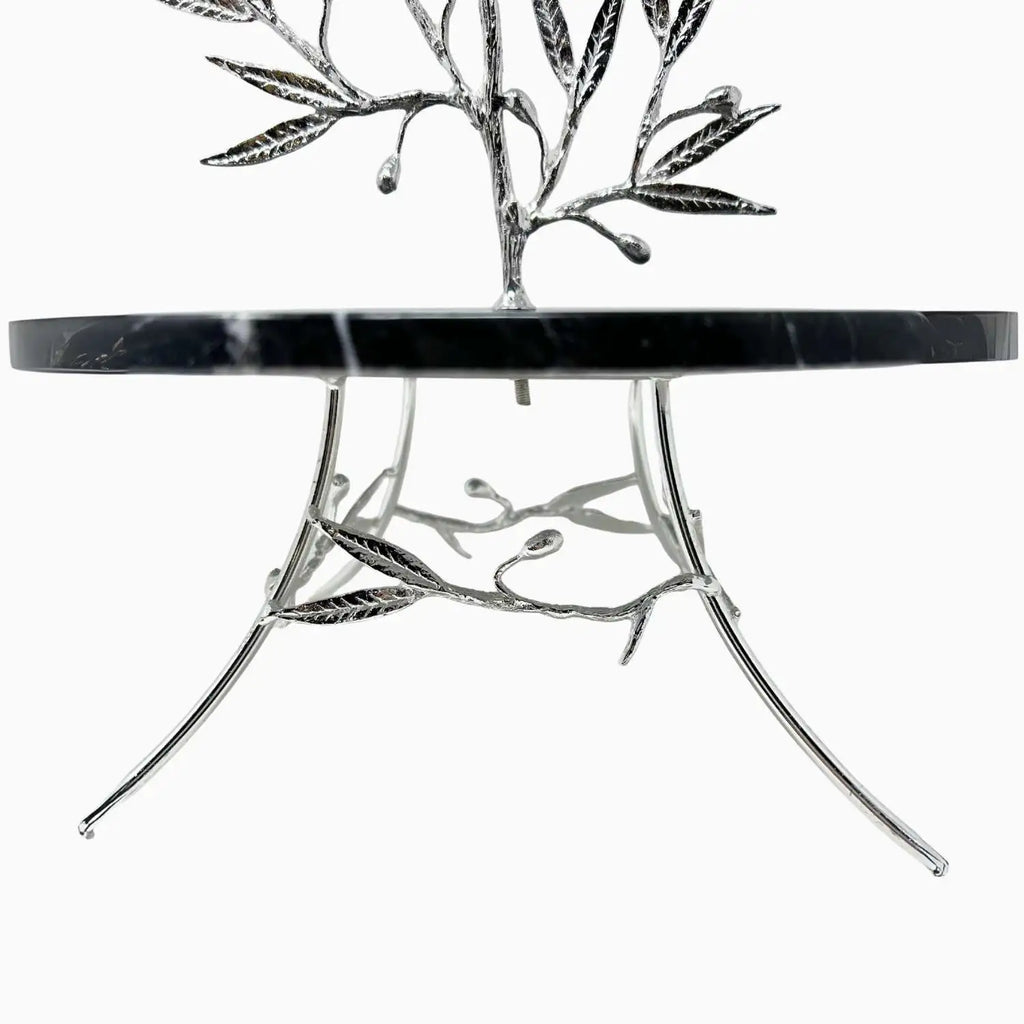 Round marble dish with silver leaf-like legs on a white background