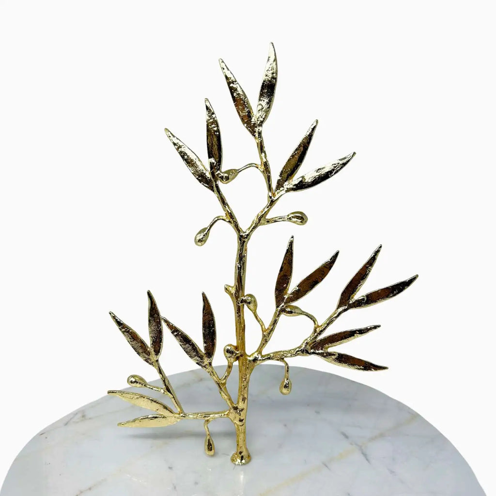 Gold leaf branch decorative item on a marble base with a white background