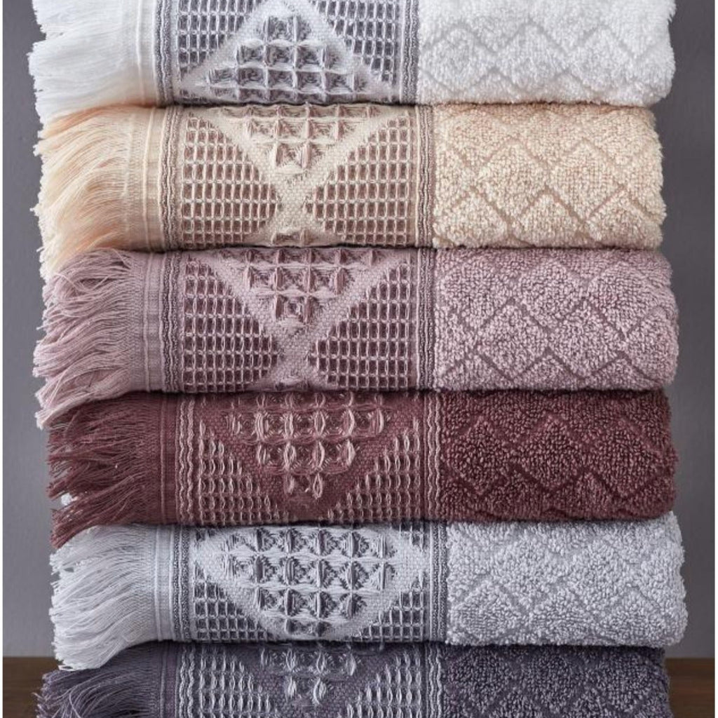 A set of six folded cotton towels in assorted colors, featuring a geometric pattern and hanging on a rack.