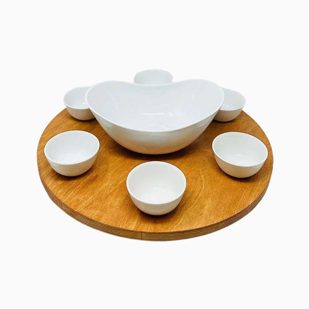 Set of white bowls on a wooden turntable against a white background