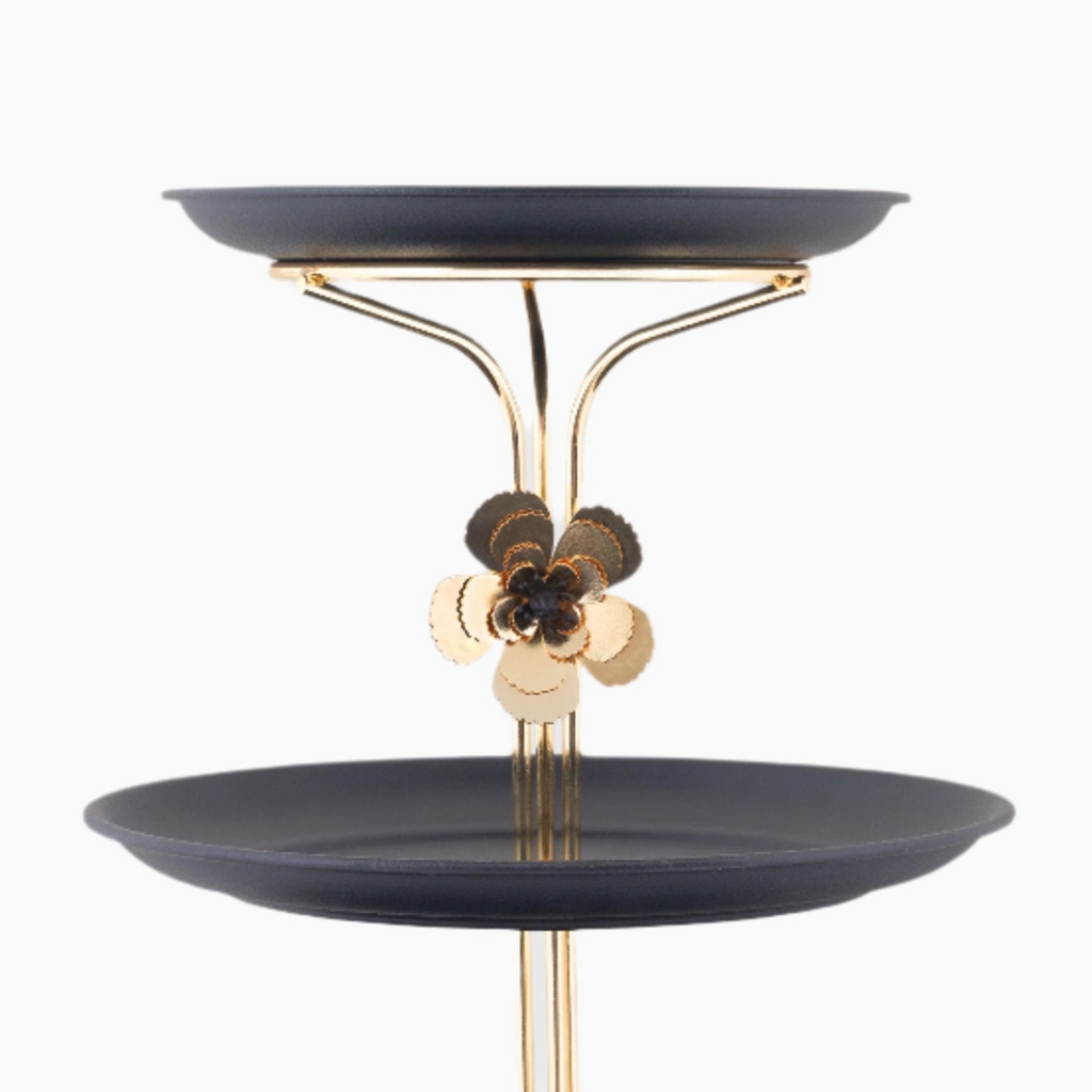 Two-tiered black tray with gold metal stand on a white background