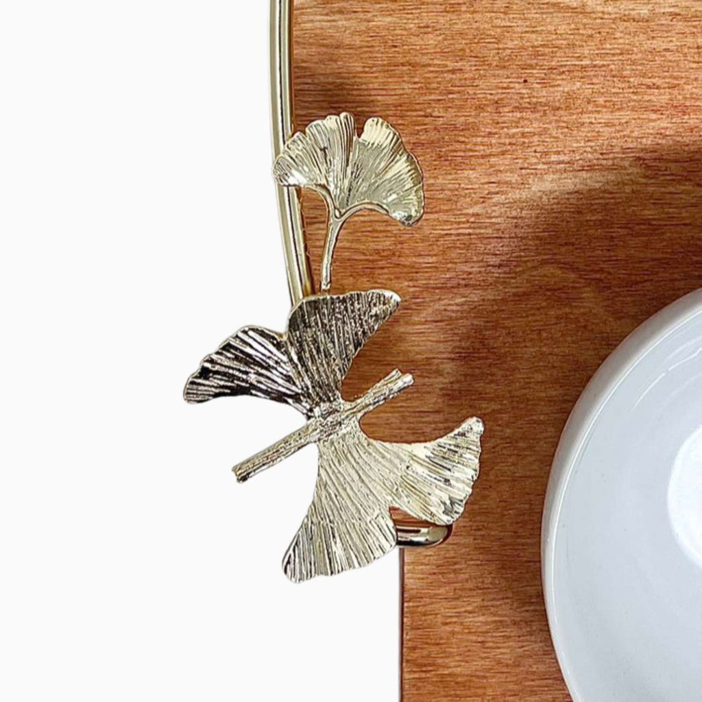 Decorative leaf-shaped gold and silver clip on a wooden tray with a white bowl.